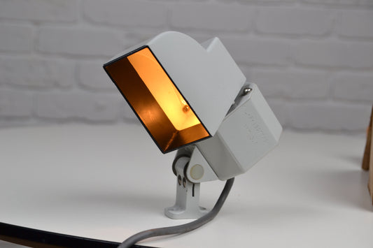Military light fixture wall lamp on a white surface against a gray brick wall.