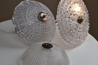 Three crystal-like lampshades on a white surface with a blurred background