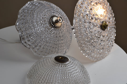 Three crystal-like lampshades on a white surface with a blurred background